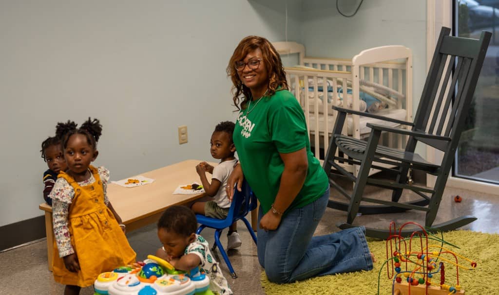 Kids and volunteers in a nursery classroom environment.