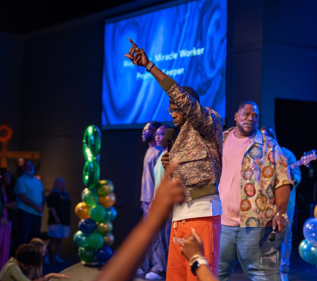 Pastor leading worship with the congregation engaged.